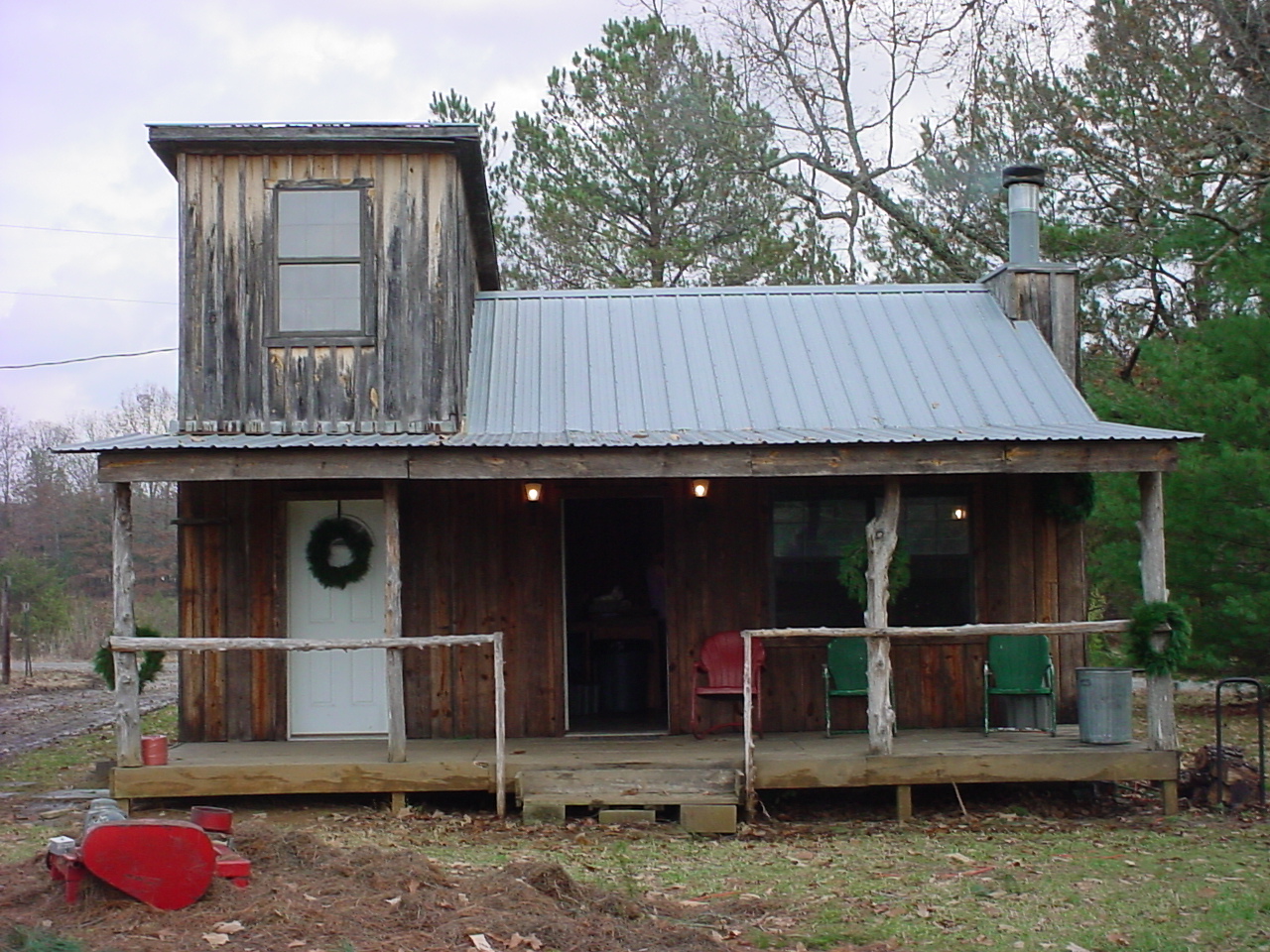 The rustic wooden cabin with a wreath on the door and a tin roof