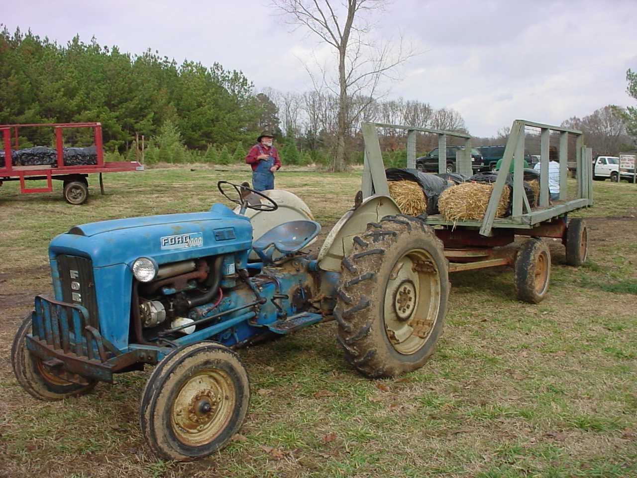 A blue Ford tractor hitched to a wagon with hay bales